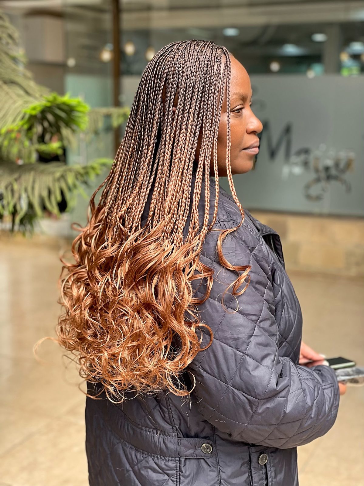 Client wearing long knotless braids with curly ends styled at Maya's Salon in Nairobi